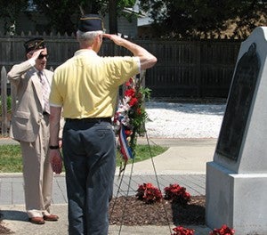 Veterans Kermit Kelly, left, and Curtis MacKenzie salute the wreath they placed at the World War II memorial at Cedar Hill Cemetery during the American Legion Norman R. Matthews Post 57 ceremony on Monday.