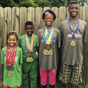 The Rose children wear the impressive collection of hardware they earned during the USATF and AAU Junior Olympic events this year. From left: 7-year-old Michailyn Rose, 10-year-old Michail Rose, 12-year-old Michaela Rose and 14-year-old Michael Rose Jr. (Marcia Rose photo)
