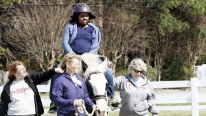 John Yeates Middle School student Sonye Taylor rides Hanni, a therapy horse at Equi-Kids Therapeutic Riding Program in Virginia Beach, on Wednesday as volunteers, from left, Cheryl Malloy, Susan Watkins and Carolyn Stamm assist.
