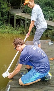 Nansemond River Preservation Alliance members Boo Van Straten and her son, Jack, collect water samples in the Western Branch region of the Nansemond River. 