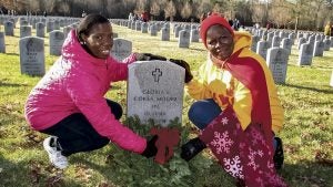 Jessica Coker and Dr. Patricia Coker-Bell place a wreath at the grave of their sister, Gloria L. Coker Moore, during Saturday’s wreath-laying at Albert G. Horton Jr. Memorial Veterans Cemetery. A fourth sister, Everline Coker, also is buried there. All four sisters served in the military. 